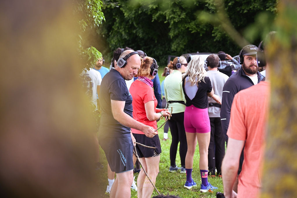 Un groupe marche dans l'herbe avec des bâtons, casques sur les oreilles